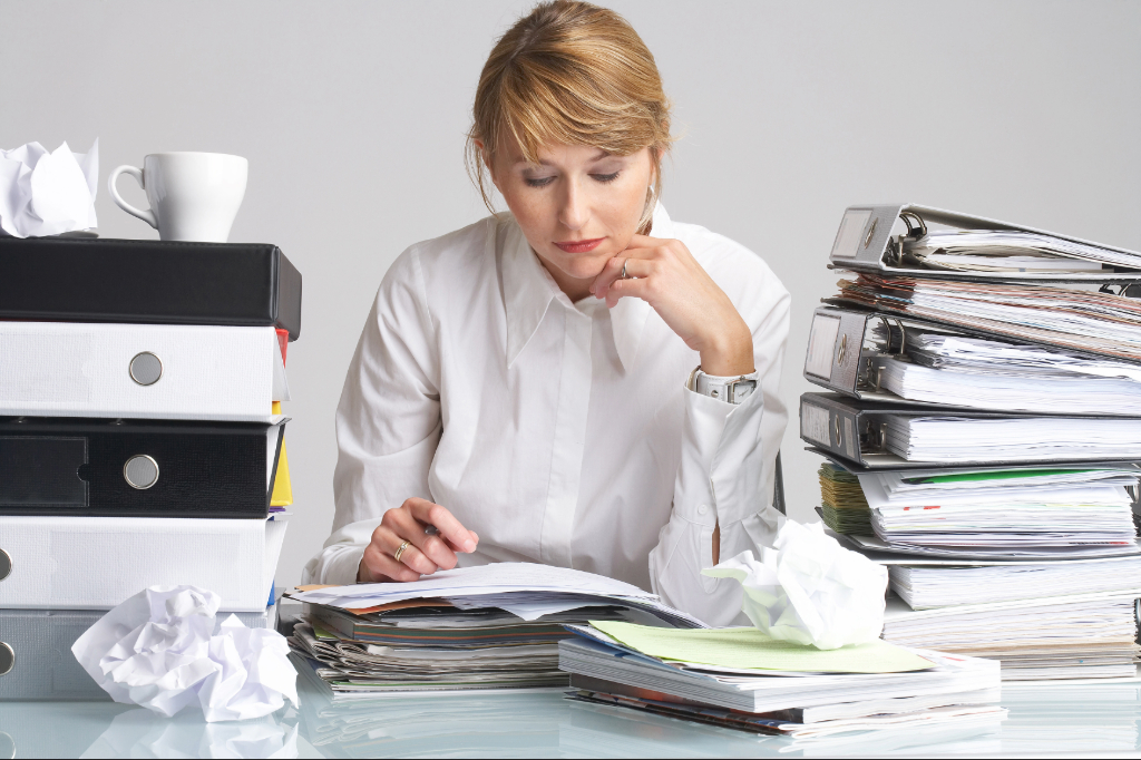 Hausverwalterin mit Papierstapeln – der Alltag vor Qlomb